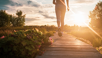 woman running on boardwalk at sunrise